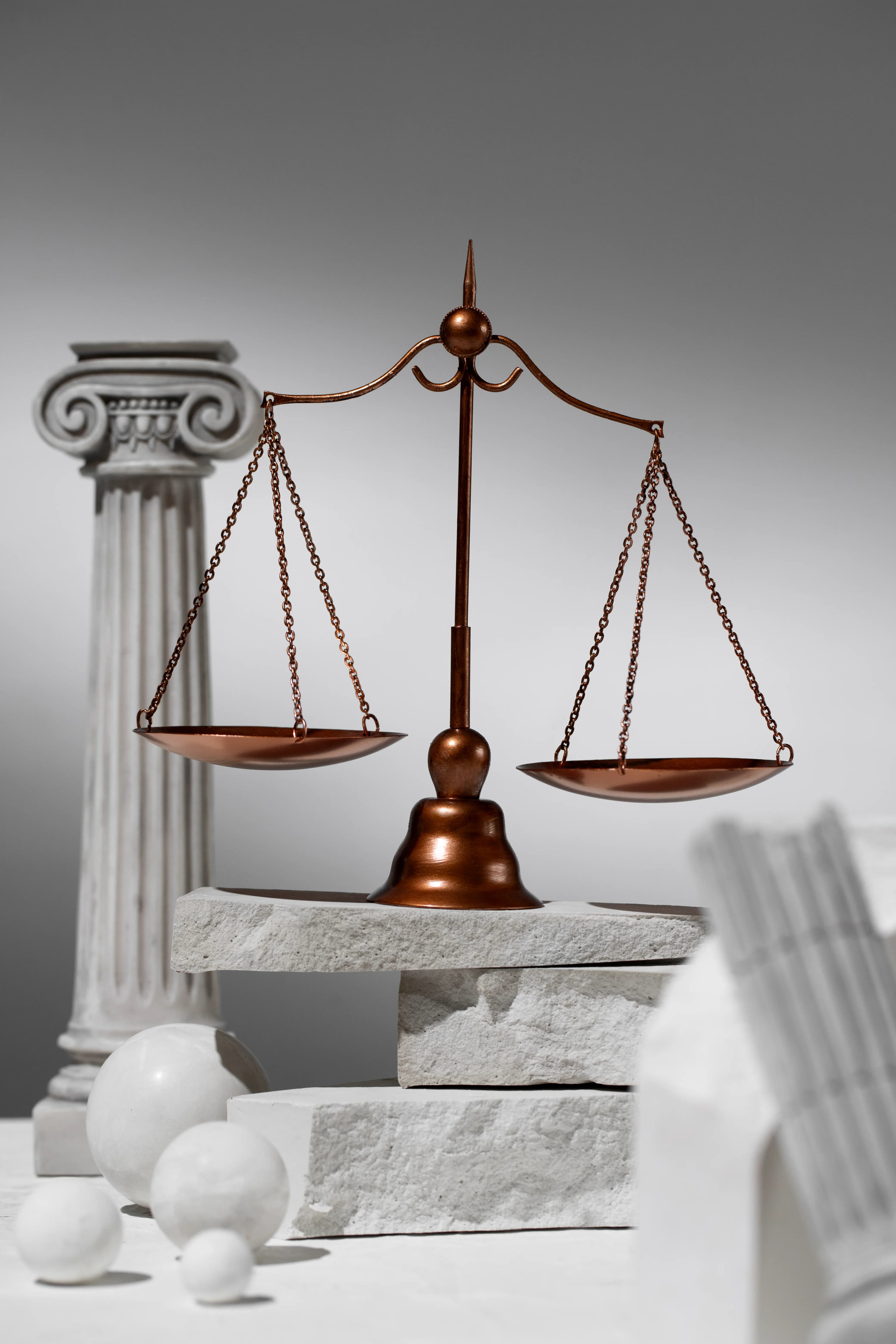Bronze scales of justice beside a classical column